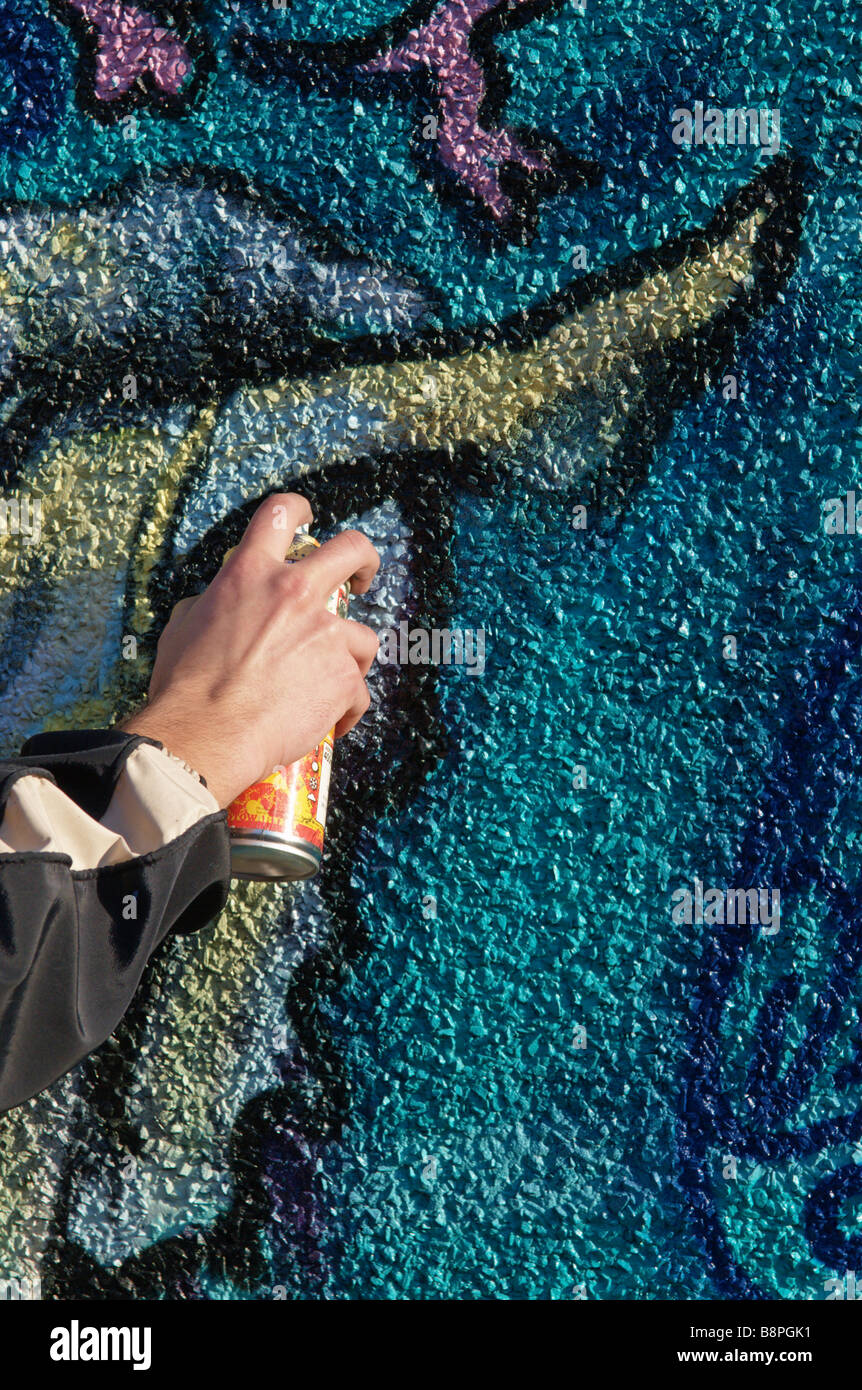 Hand of Graffiti artist using spray paint can and painting wall mural Stock Photo