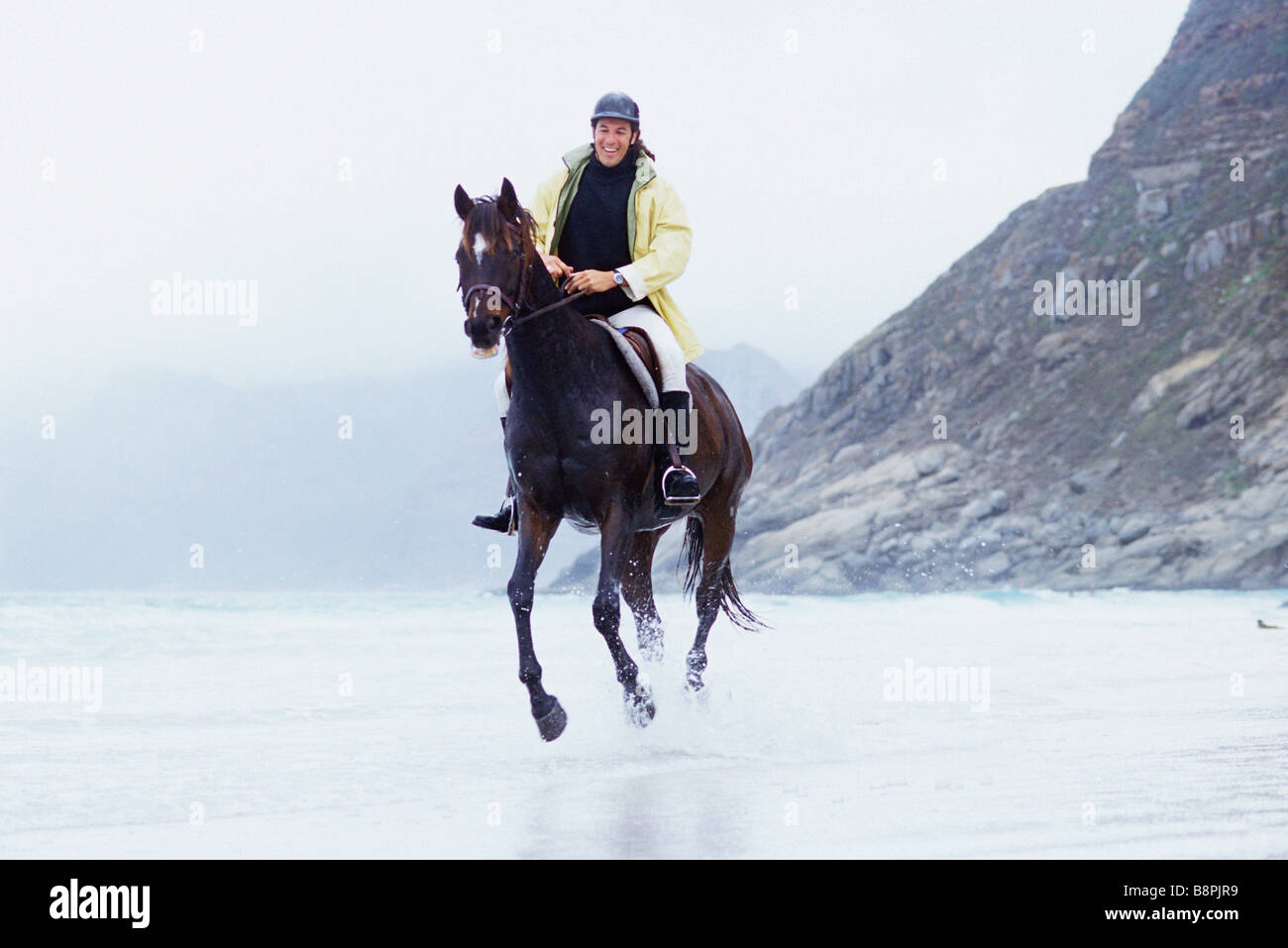 Man riding horse on beach Stock Photo - Alamy