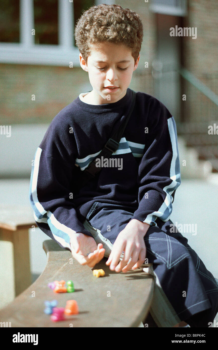 Boy sitting on bench, playing game Stock Photo