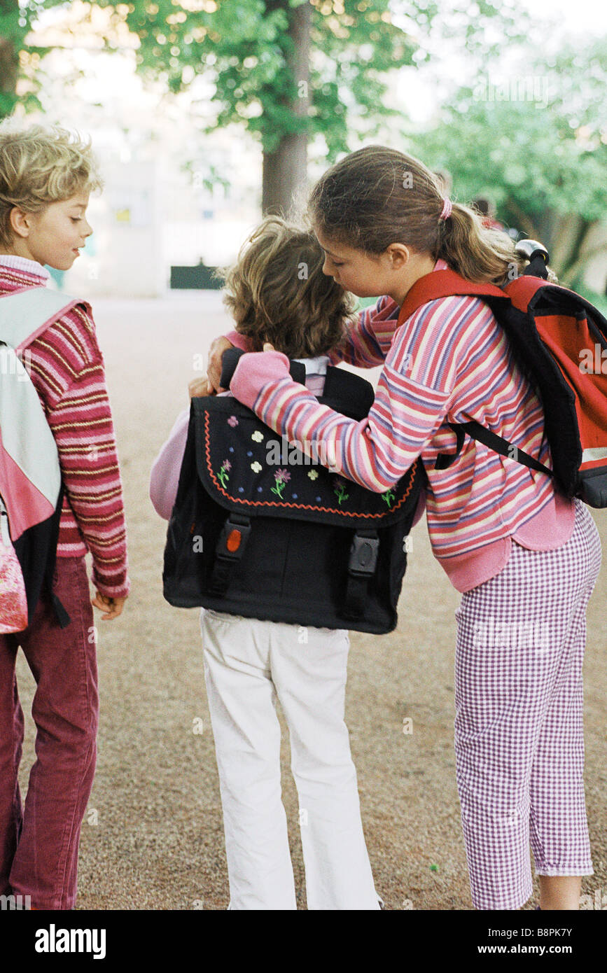 Girl helping younger sister put on backpack Stock Photo - Alamy