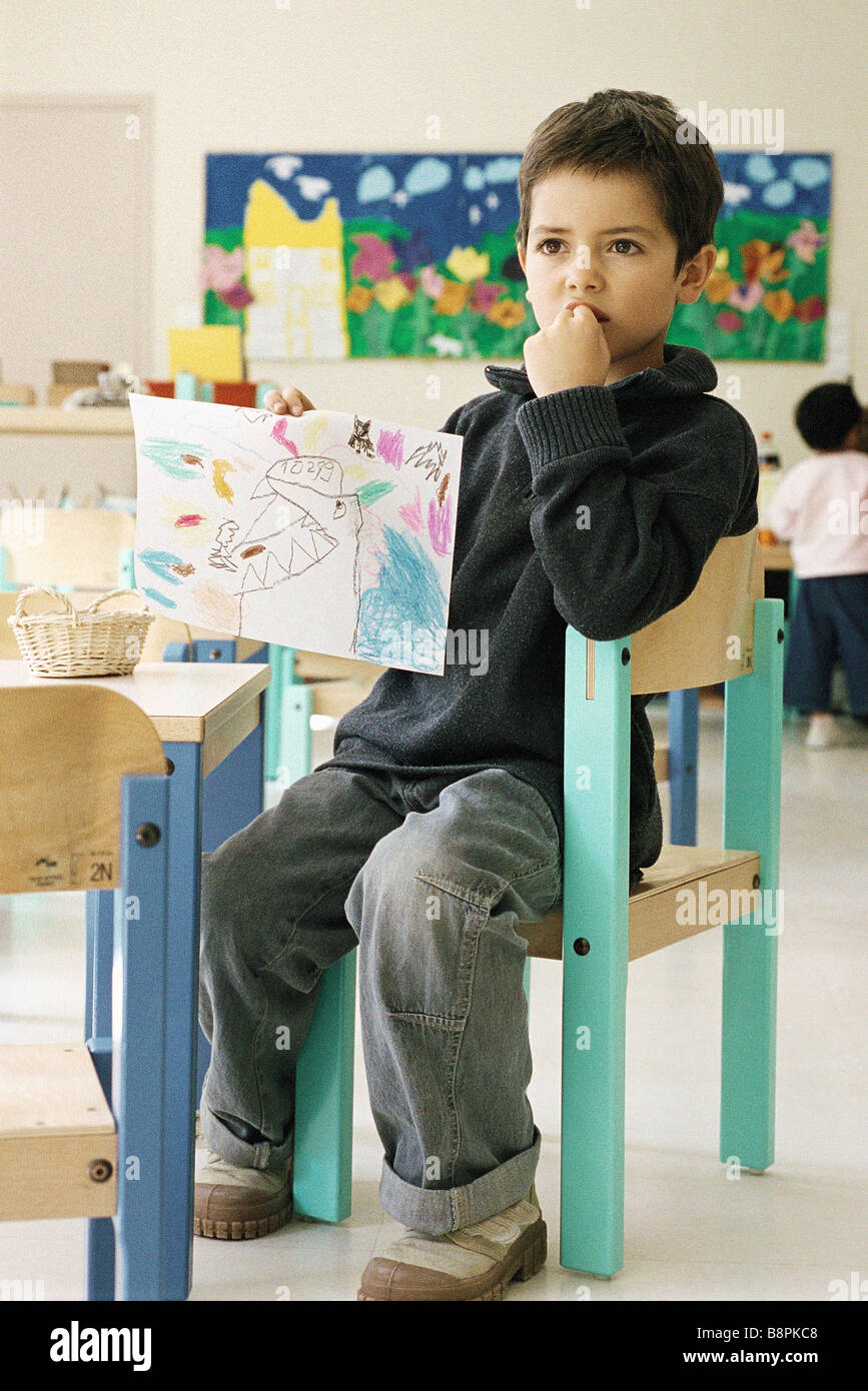 Boy holding up drawing in class room Stock Photo - Alamy