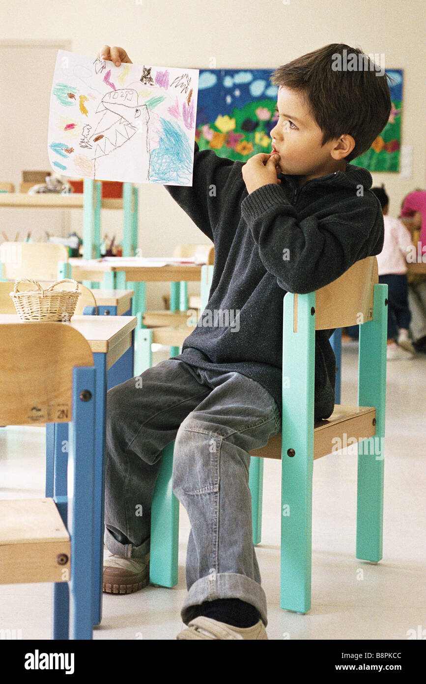 Boy holding up drawing in class room Stock Photo - Alamy