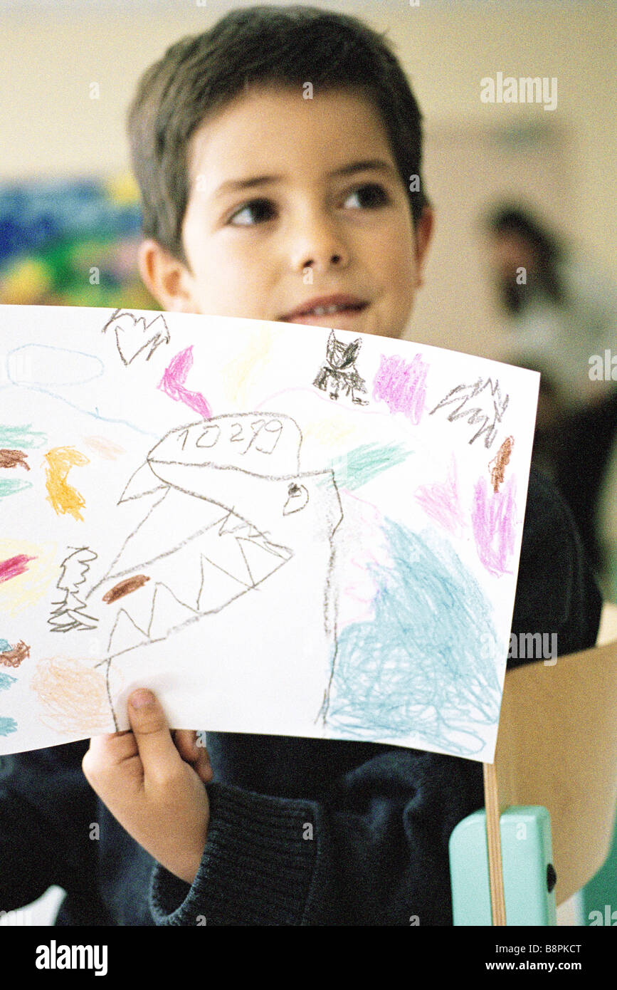 Boy holding up drawing in class room Stock Photo - Alamy