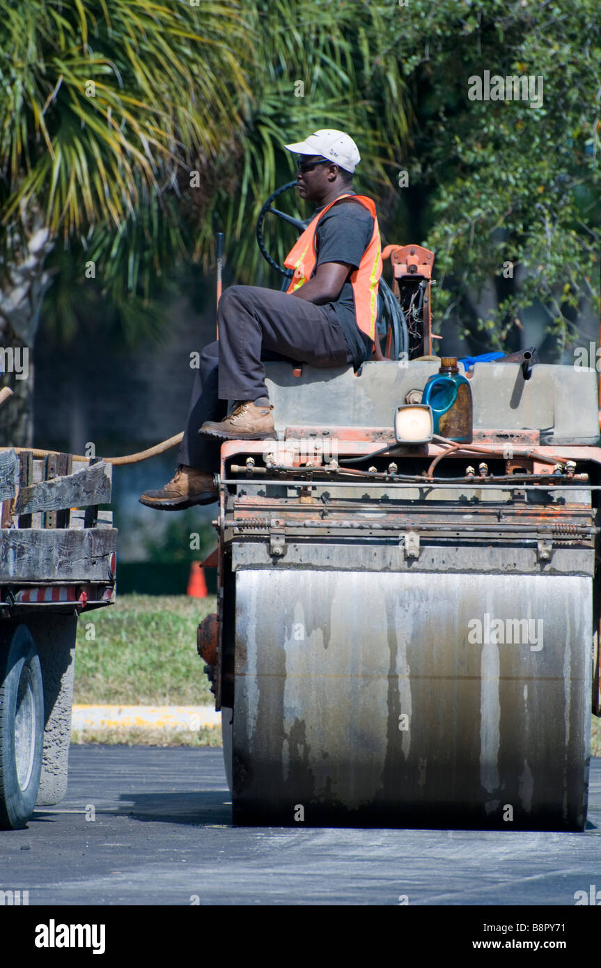 Construction worker sitting on the heavy duty machine in new asphalt