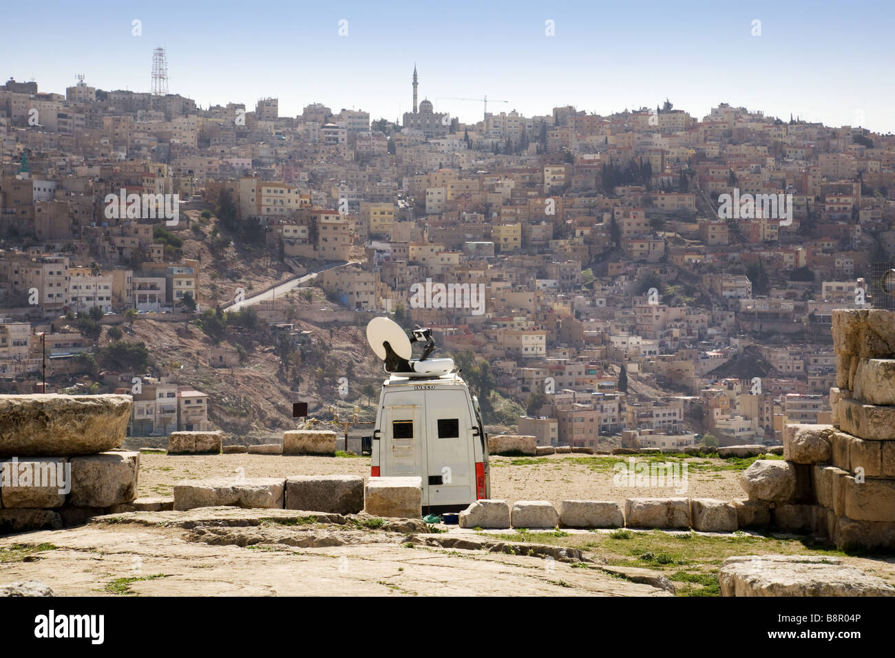 A modern TV van seen in the ancient Citadel of Amman, Jordan, with the city in the background Stock Photo