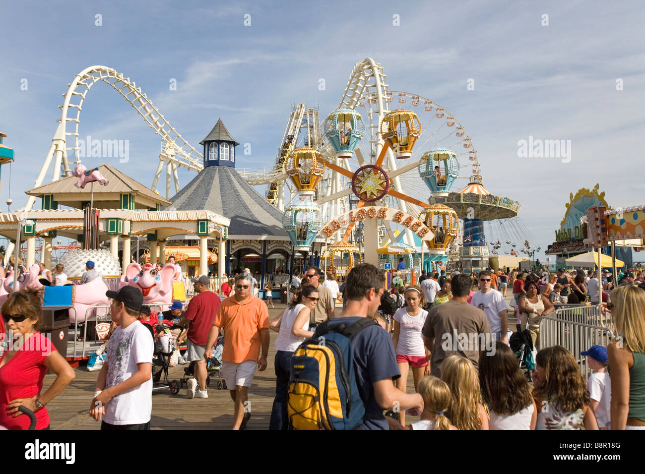 An amusement park with a crowd of visitors at the ocean shore Stock