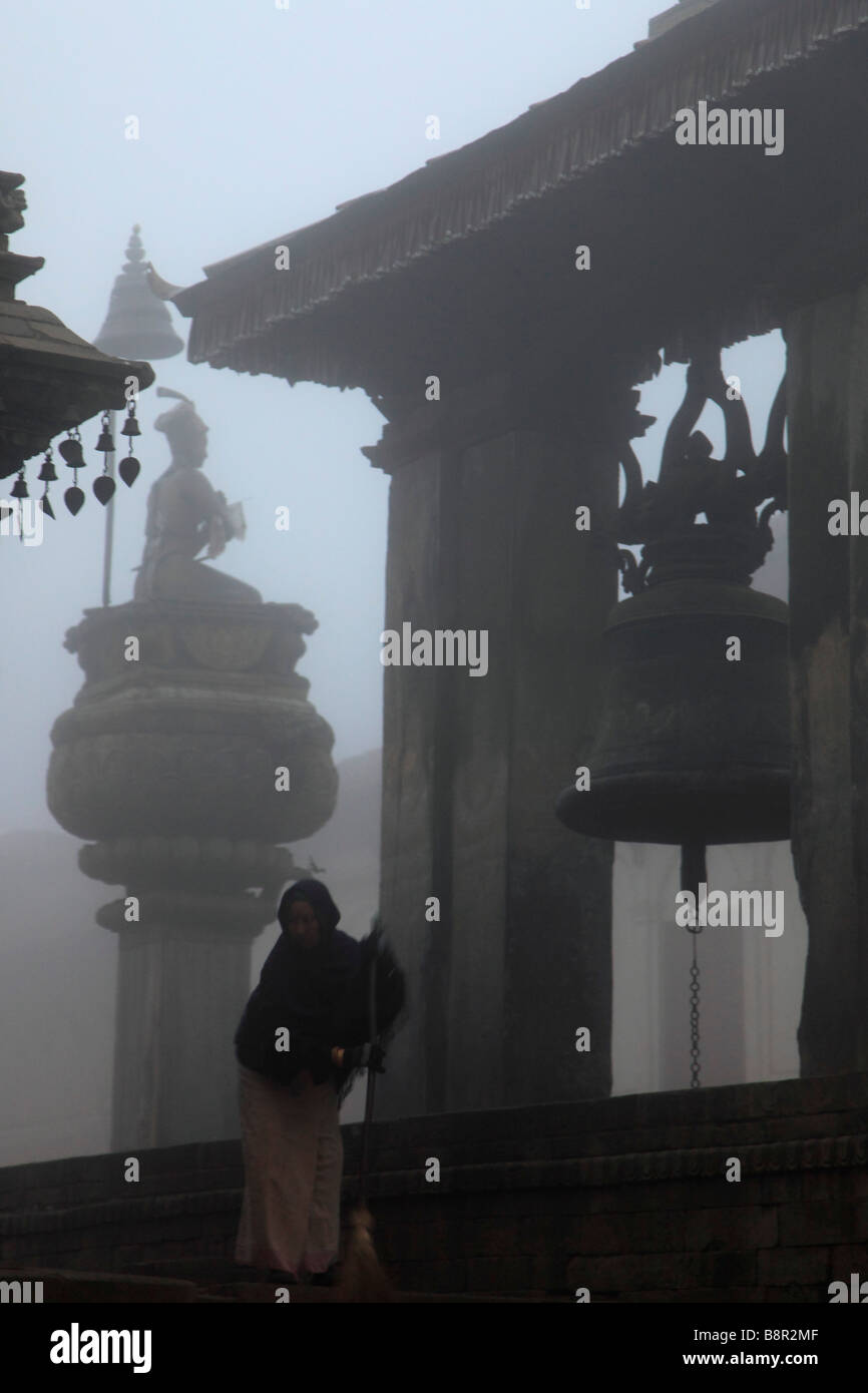 Nepal Kathmandu Valley Bhaktapur Durbar Square King Malla Column Taleju Bell sweeping woman Stock Photo