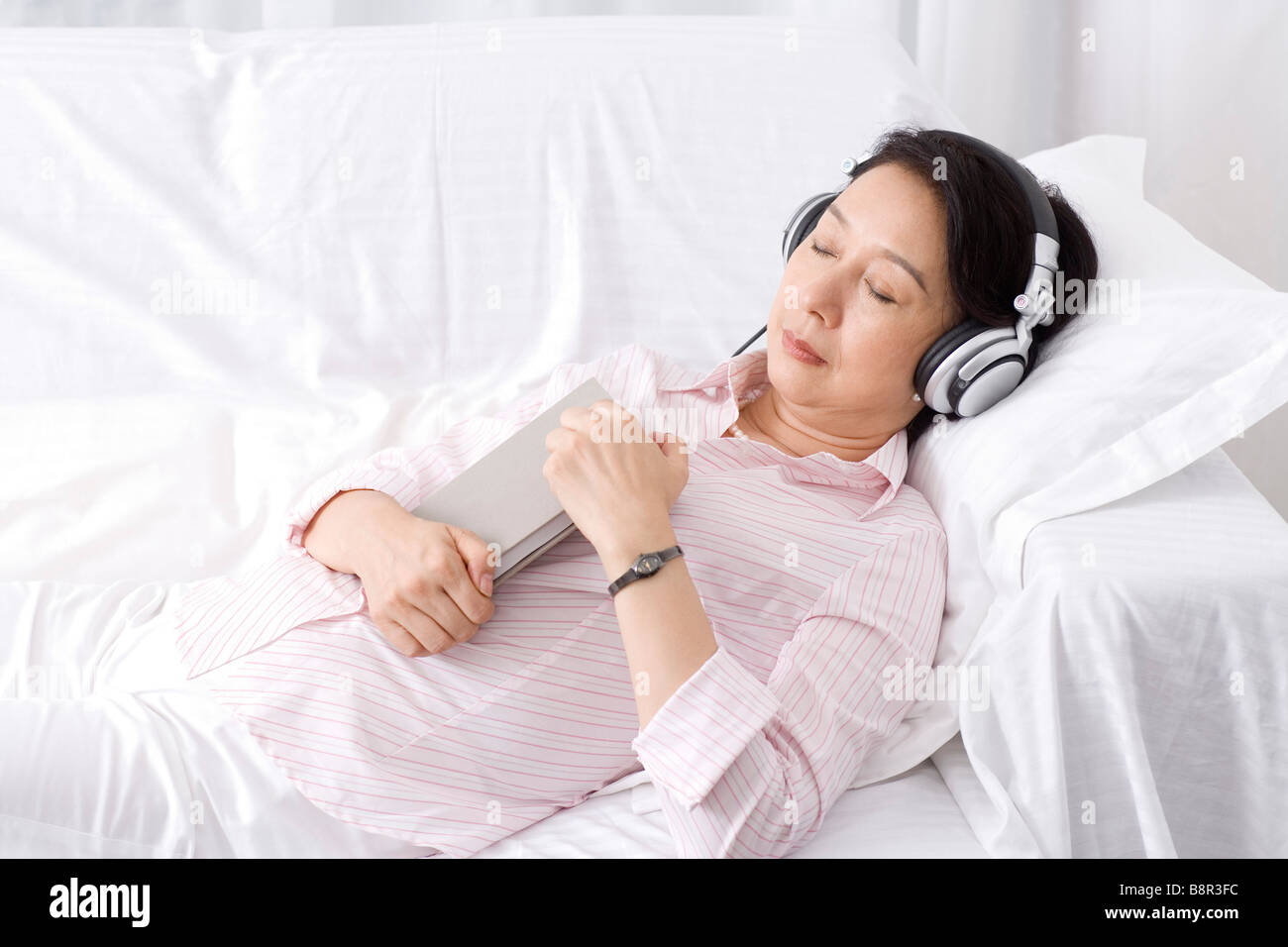 Senior woman wearing headset lying on sofa sleeping Stock Photo Alamy