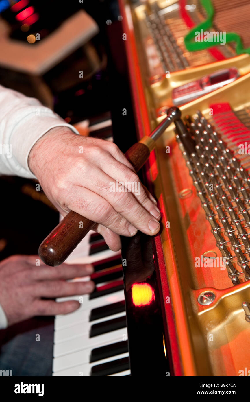 Detail of the hands of a man piano tuner tuning a grand piano before a concert, UK Stock Photo
