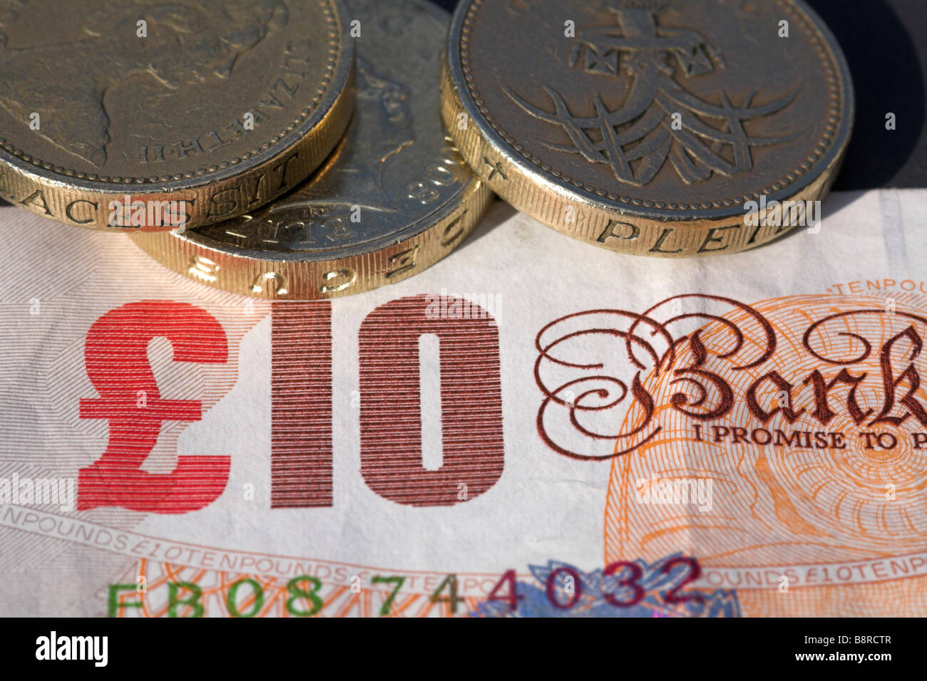Bank of England ten pound banknote with pile of pound coins. Stock Photo