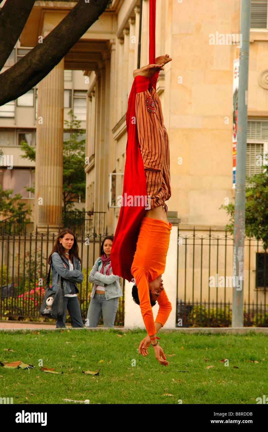 hanged upside down boys girls catch attention pick me up clown men women meeting casual Bogota South America street entertainer Stock Photo