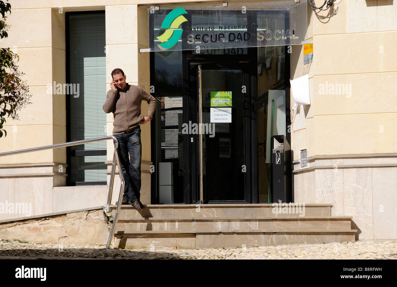 Social Security office exterior and man standing outside using a mobile phone Stock Photo