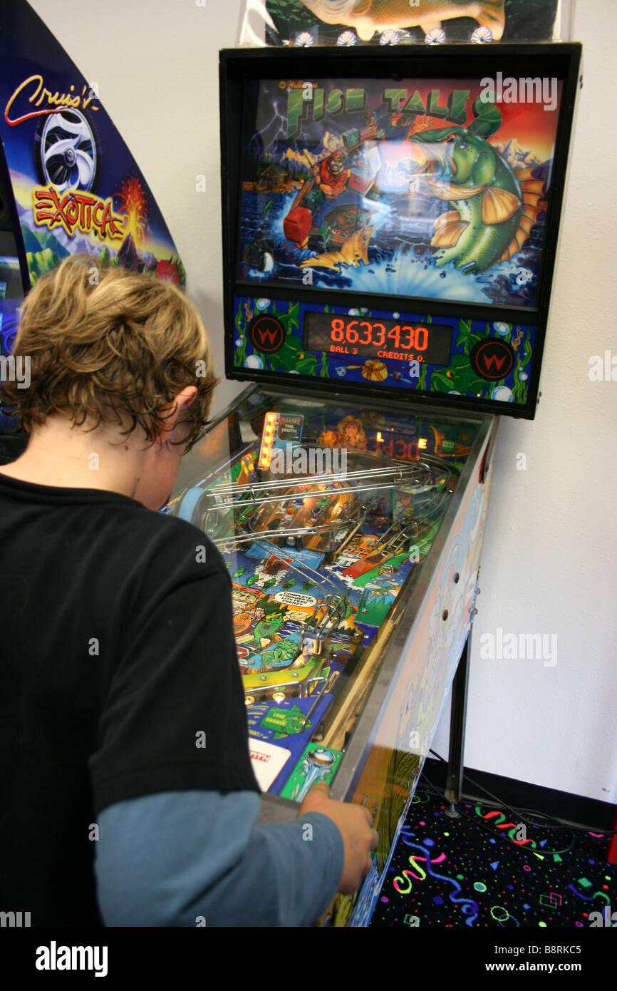 nine year old boy playing a pinball machine in arcade, united states Stock Photo