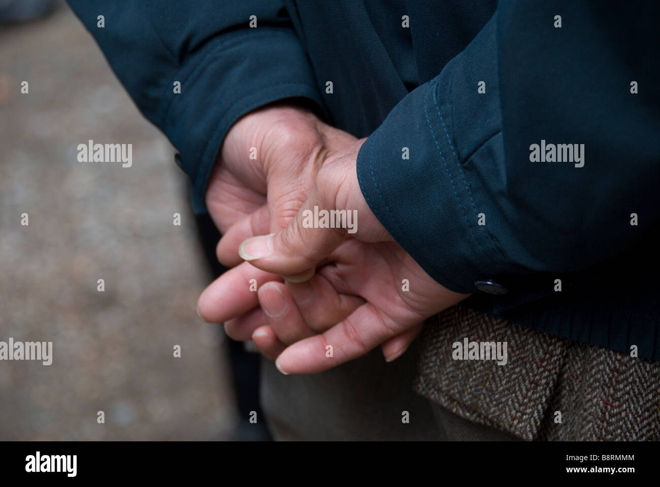 Long nailed men's hands, held behind the back of their owner Stock Photo