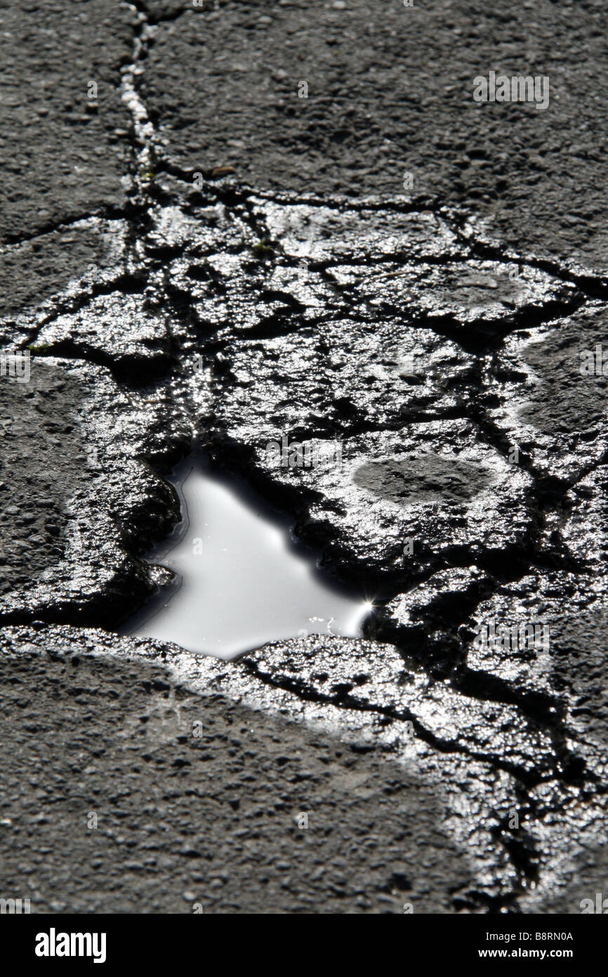 detail of hole and cracks in damaged road surface outdoors Stock Photo