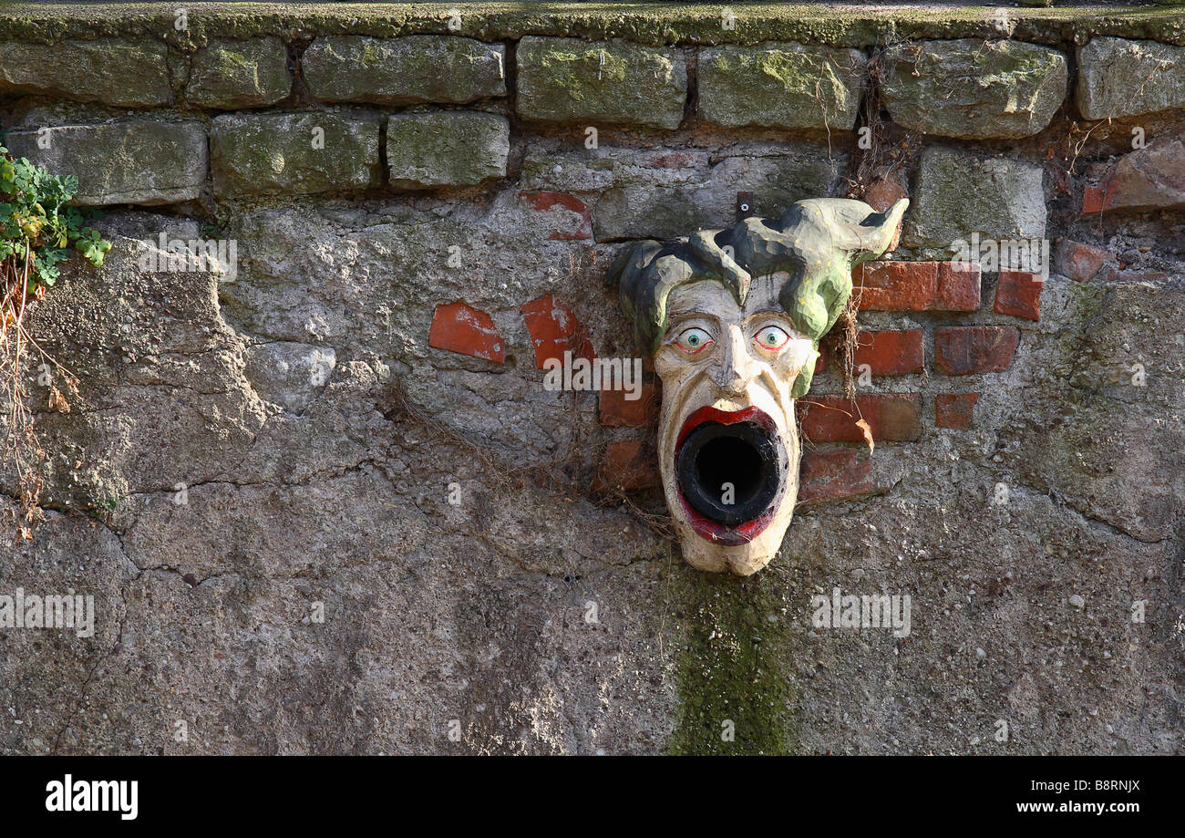 stone mask at a wall with water pipe opening as the mouth Stock Photo