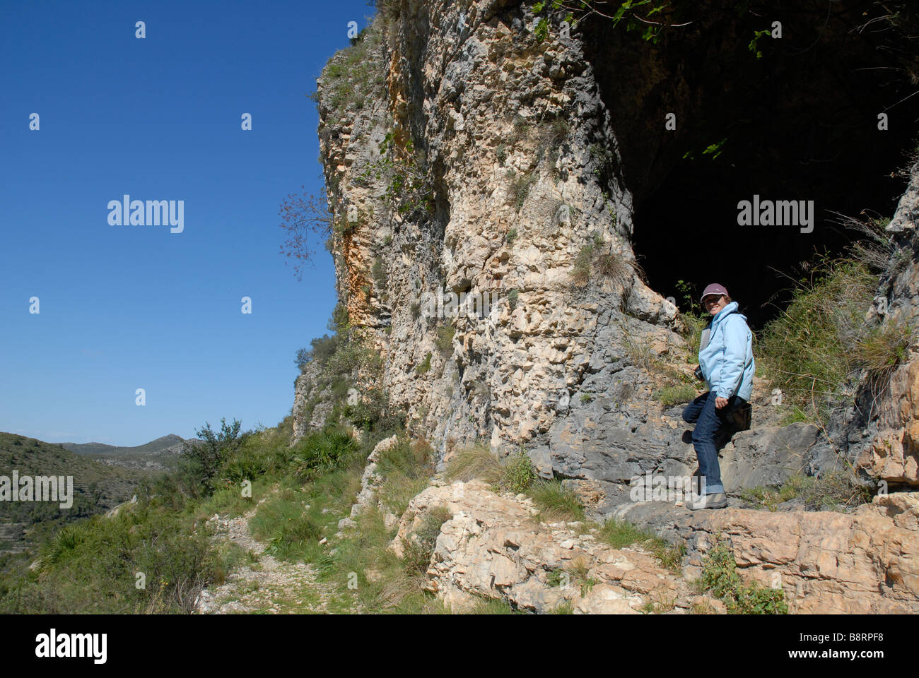 woman hiker at cave entrance off Mozarabic trail, Vall de Laguart, Benimaurell, Alicante Province, Comunidad Valenciana, Spain Stock Photo