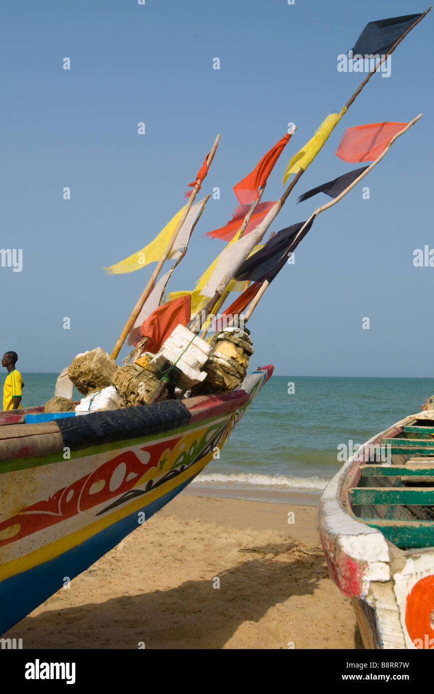 Painted fishing boats and colourful flags in the wind on a beach in Nianing Senegal West Africa Stock Photo
