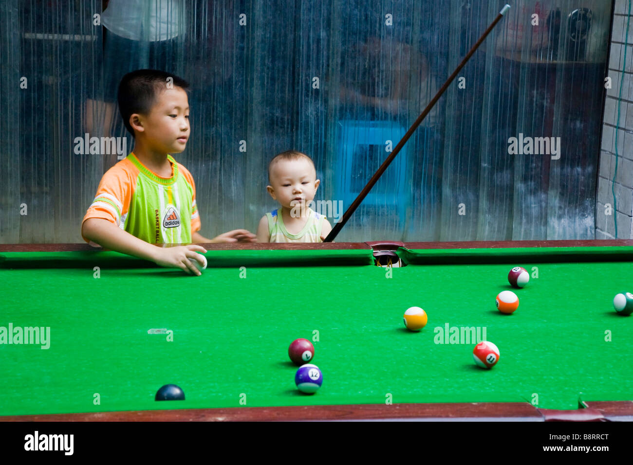 Small chinese boy teaching his baby brother to play pool, Chongqing city, southwestern China. Stock Photo