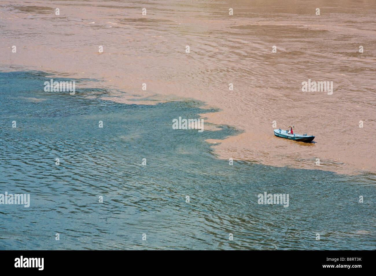 Small boat on the meeting of the brown Yangtze and the blue Jialing river waters in Chongqing city, southwestern China. Stock Photo