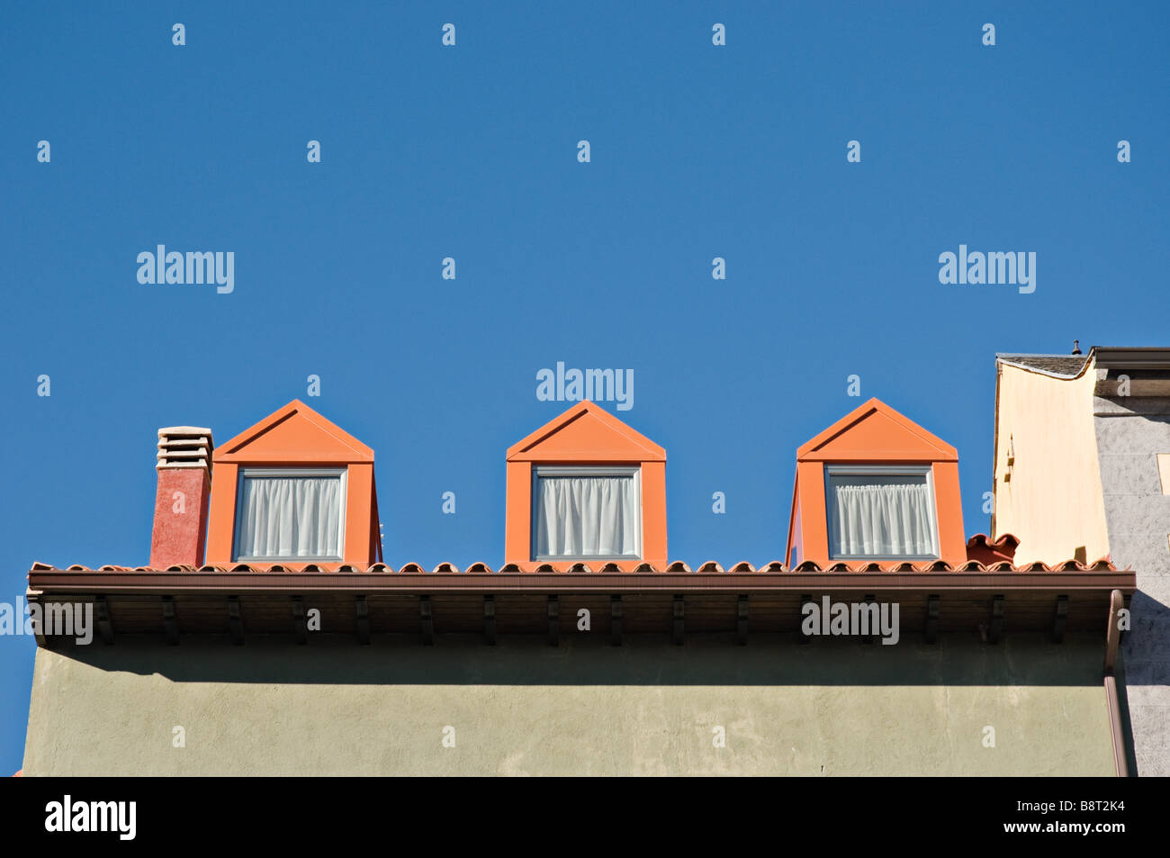3 Orange pointy windows against a blue sky Stock Photo