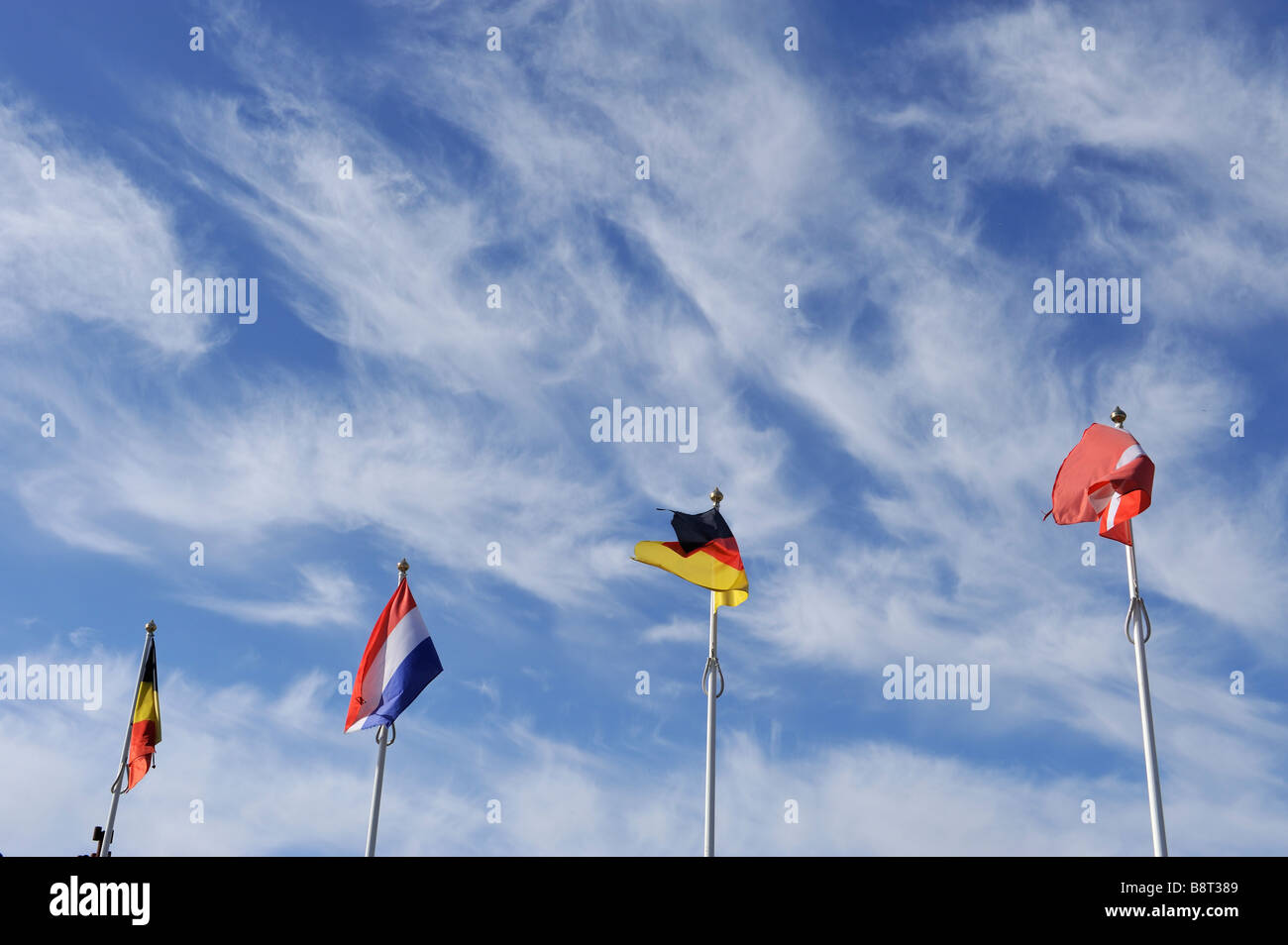 Four flagpoles under a blue sky with cirrus cloud Stock Photo - Alamy