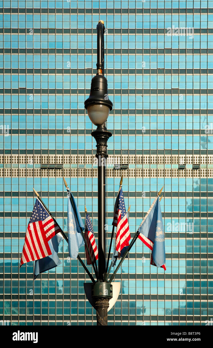 Lamp post with UN and US flags in front of the glass facade of the United Nations headquarters, UNO, New York, USA Stock Photo