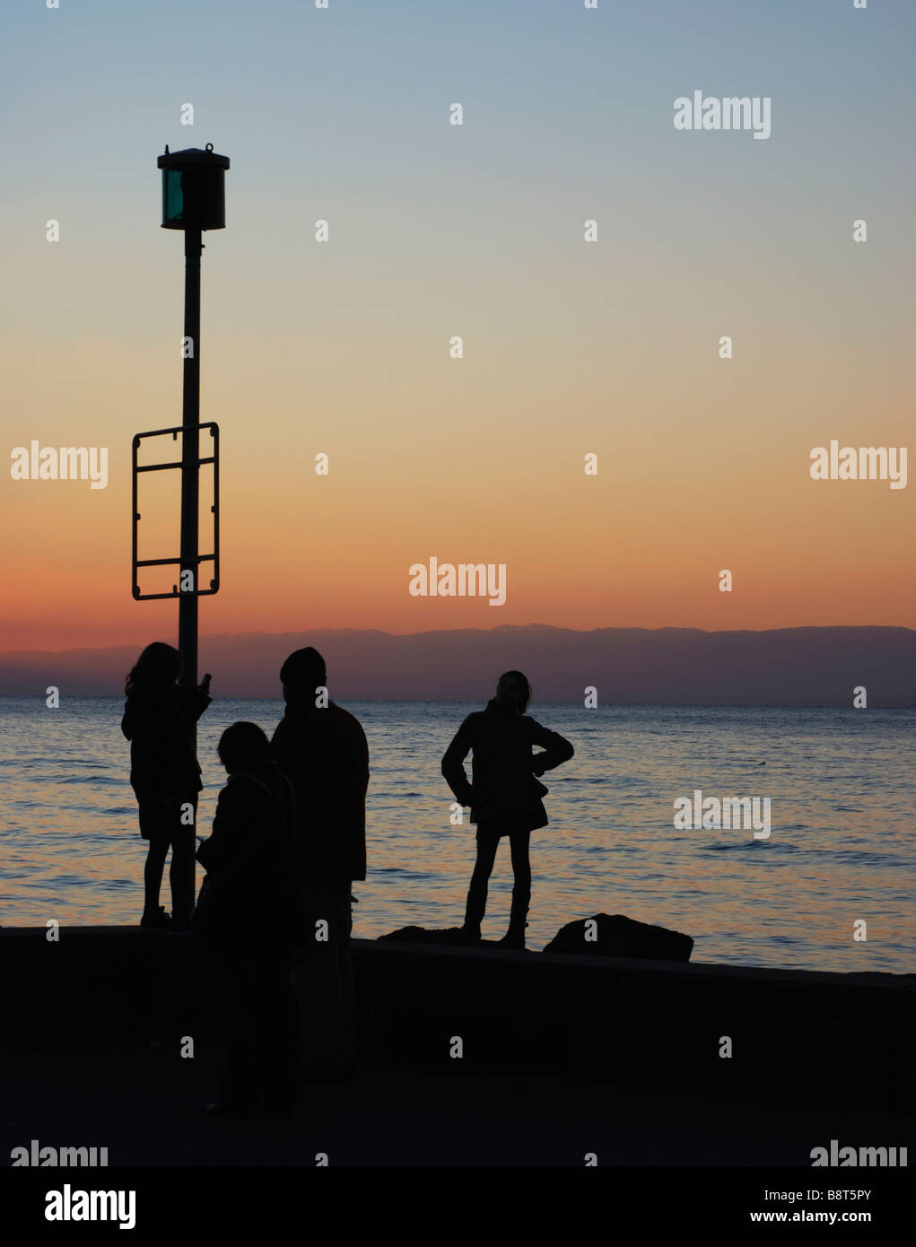 View of the sunset over Lac Leman as viewed from Lausanne, Switzerland. Unrecognisable family in the foreground in silhouette Stock Photo