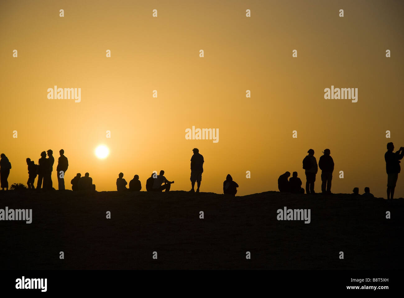 The silhouette of tourists and  locals who flock to Cap San Vincent to watch the sun set over the Atlantic Ocean. Stock Photo