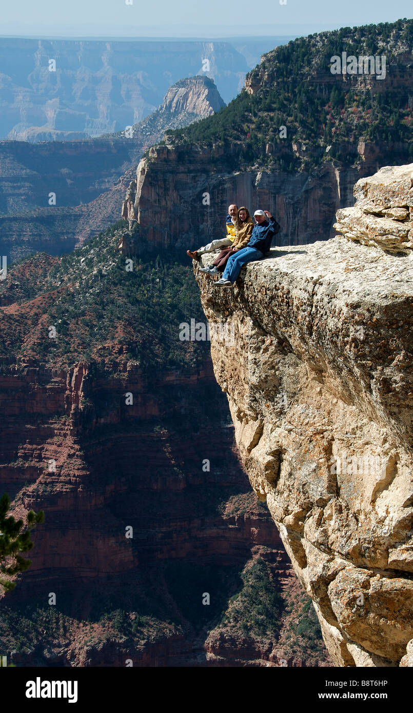 Three people sitting on the edge Grand Canyon National Park North Rim Arizona USA Stock Photo