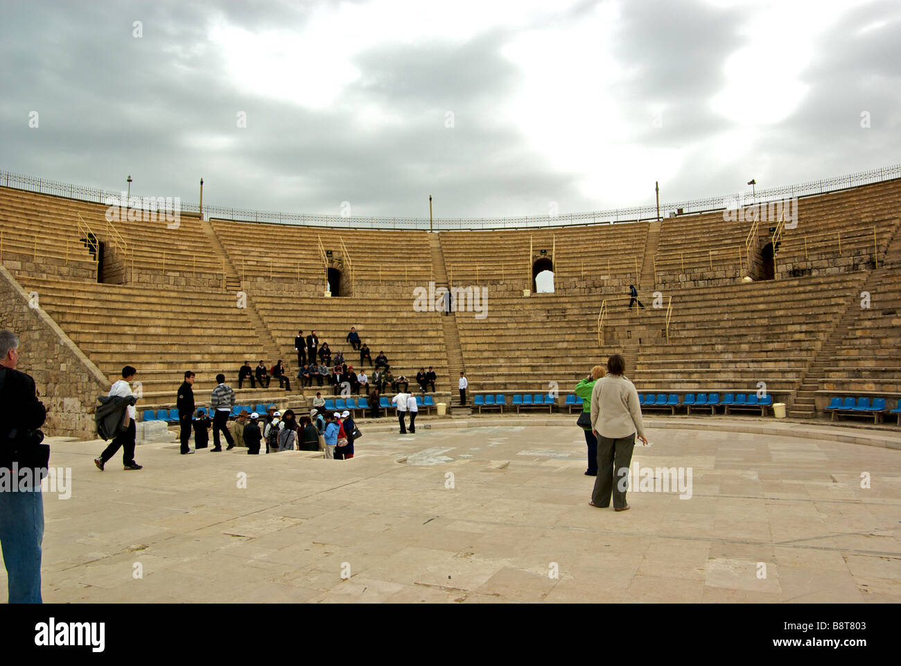 Student field trip and tourists in preserved renovated ruins of giant seaside amphitheatre overlooking Mediterranean sea Stock Photo