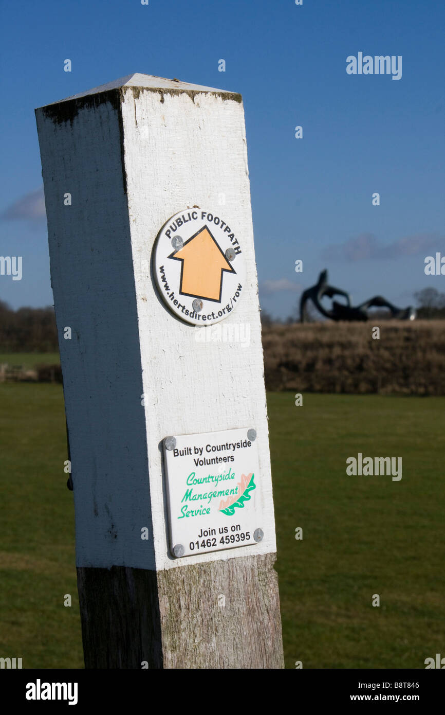 hertfordshire way public footpath signpost near perry green out of focus henry moore sculpture beyond england uk gb Stock Photo