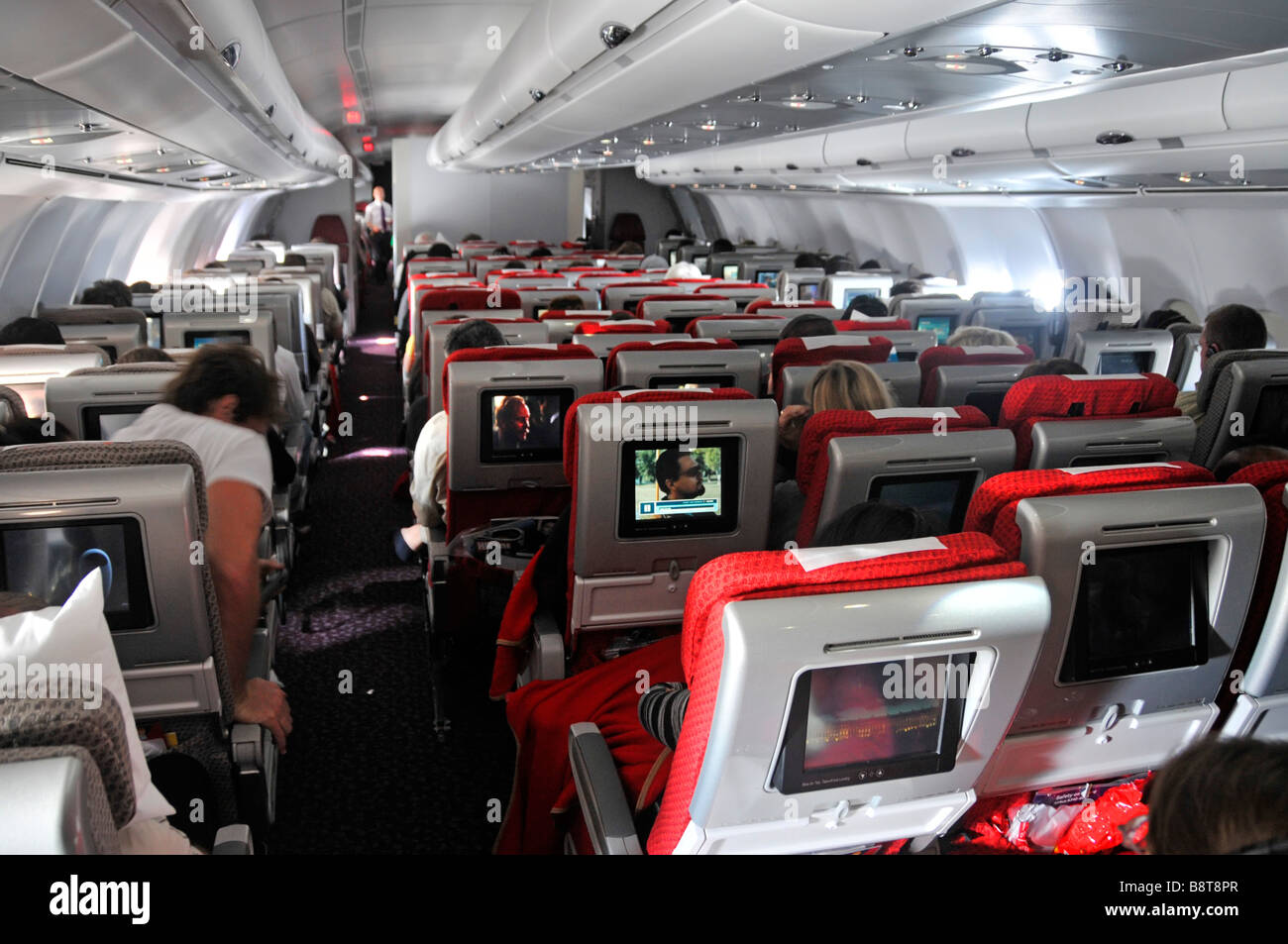 Travel by passenger plane interiors Virgin Atlantic Airbus jet airplane cabin passengers inflight TV entertainment movie film screen on back of seats Stock Photo