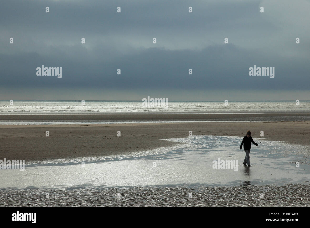 Boy walking on the beach on a stormy day Stock Photo