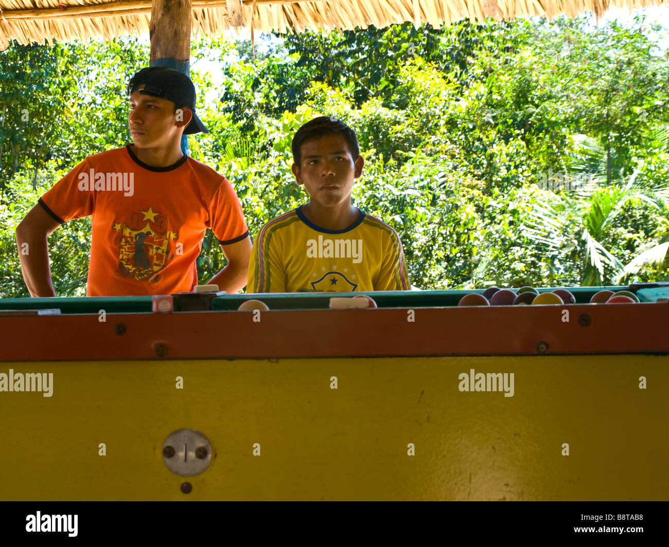 Two boys from a small village inside the amazonian rainforest near Tapajos river playing pool. Stock Photo