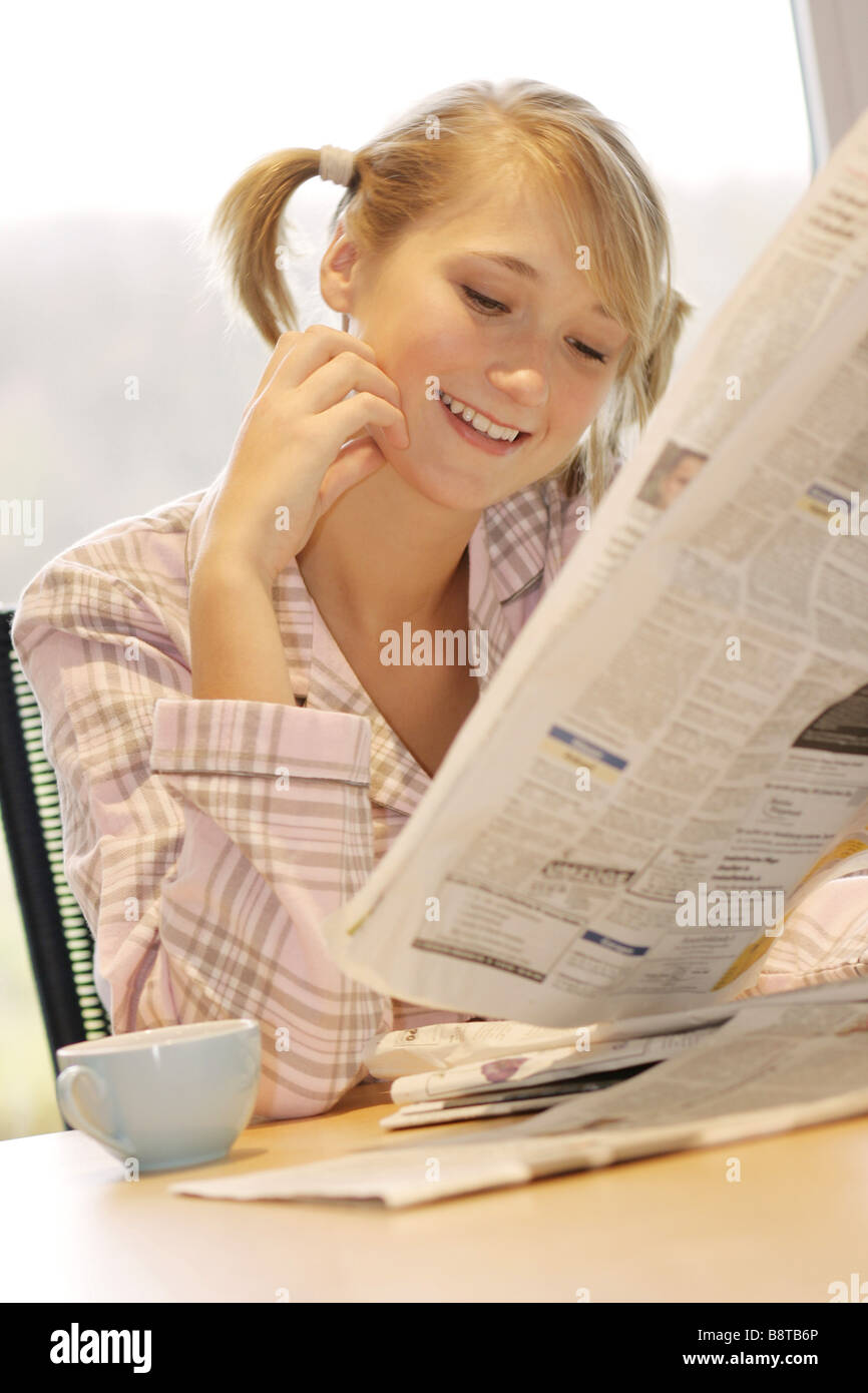 young woman with cup of coffee and newspaper in the morning, Germany Stock Photo