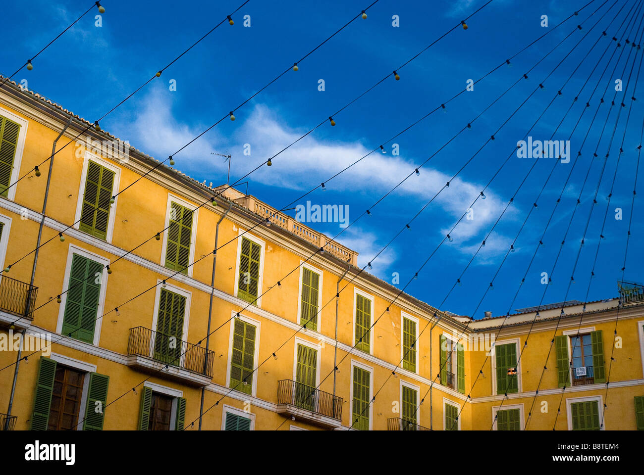 Yellow townhouses in Plaza Major with a row of lightbulbs string across. Palma, Mallorca. Stock Photo