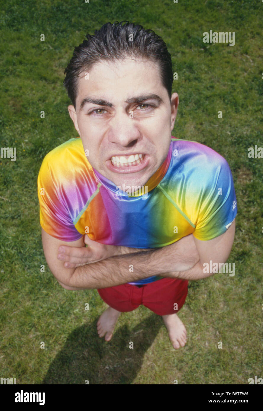 Upset Man with colored shirt and shorts standing on the lawn like a clown Stock Photo