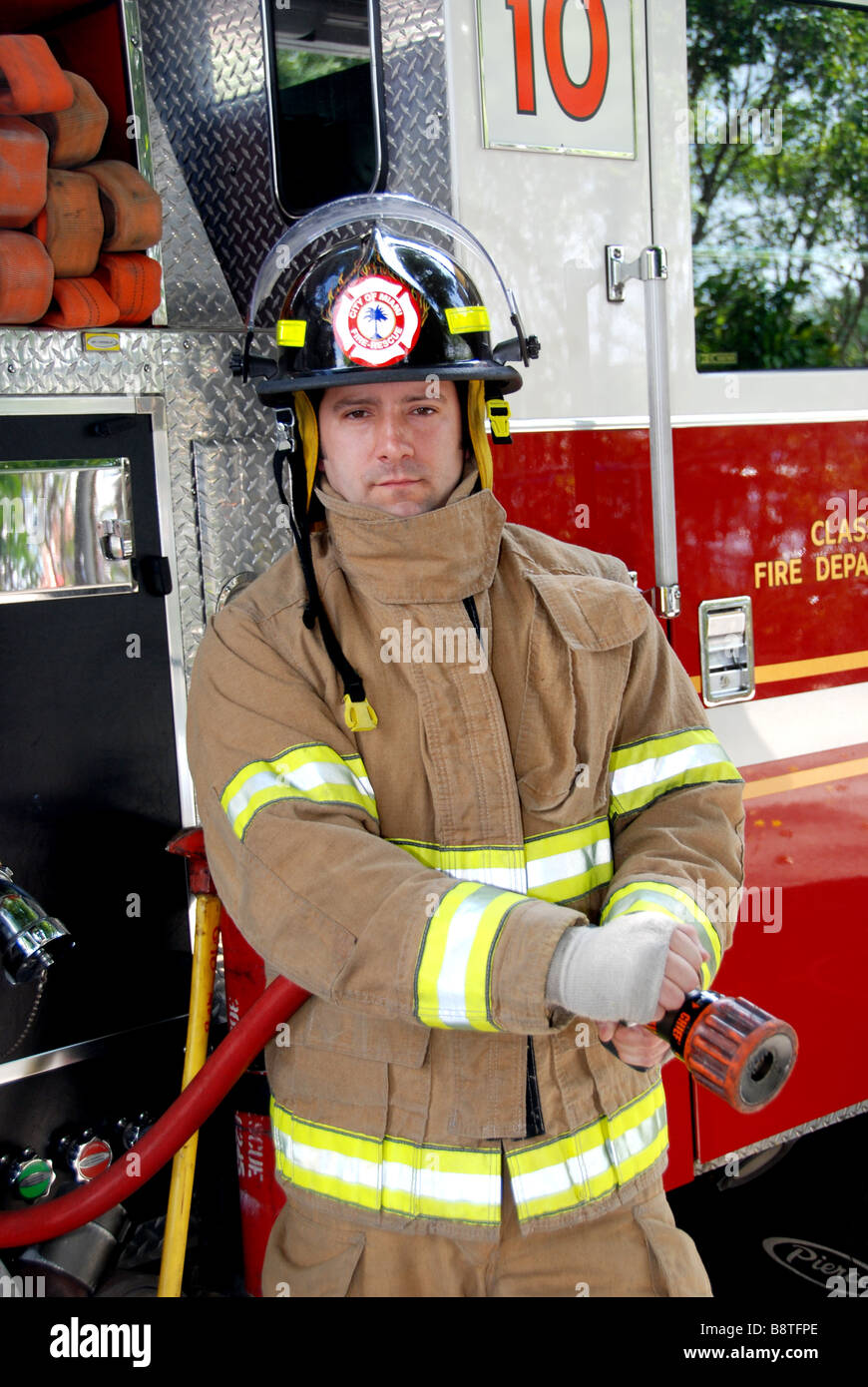 Male Firefighter  holding fire  hose in front of fire  truck  