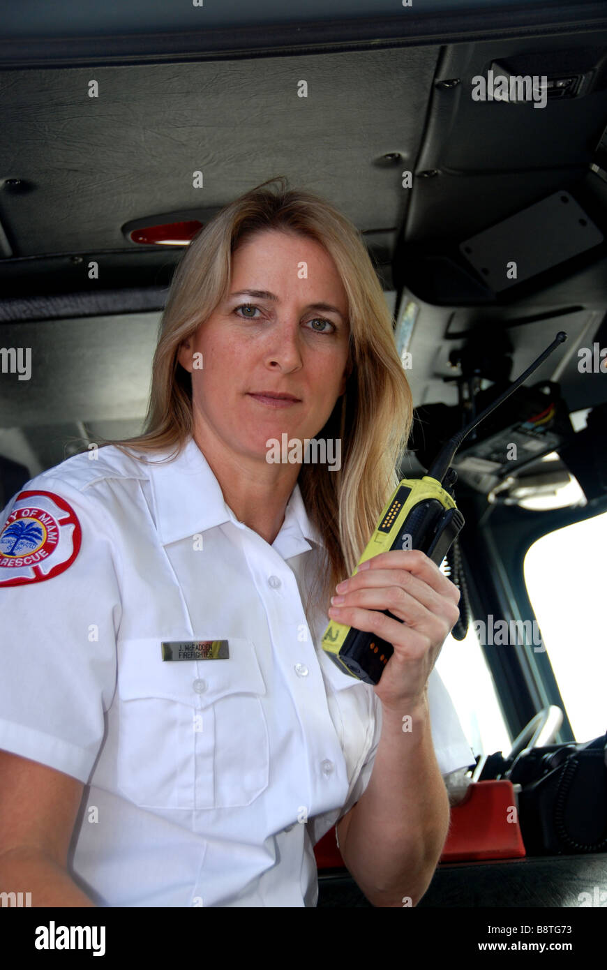 Female firefighter paramedic EMT in dress uniform talking on two way