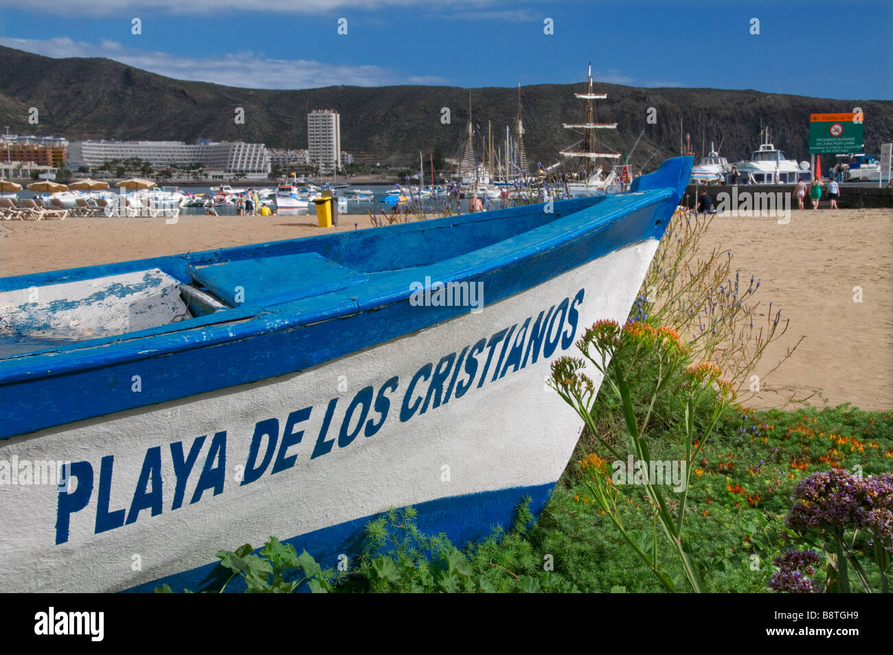 Feature traditional wooden fishing boat named 'Playa Los Cristianos' lying on Los Cristianos beach Tenerife Canary Islands Spain Stock Photo