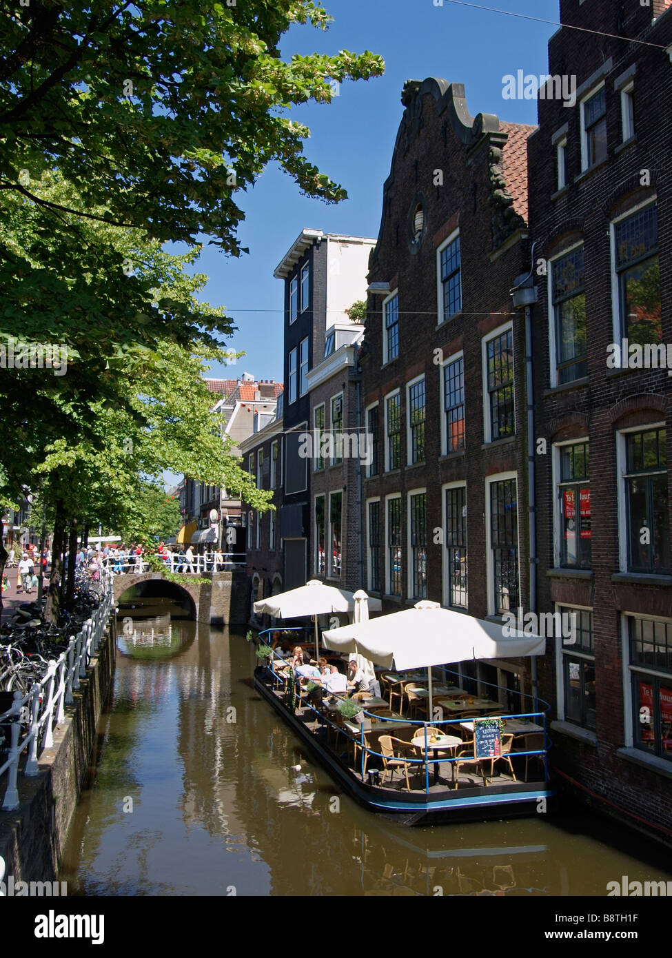 People having a drink in the sun on a canal in Delft the Netherlands Stock Photo