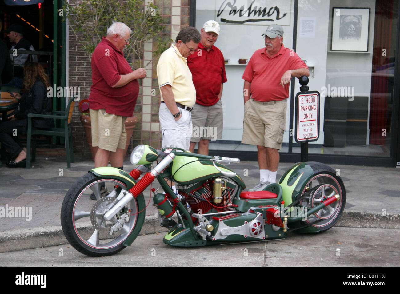Four middle aged white men looking at a lowrider motorcycle in Ybor City Tampa Florida USA Stock Photo