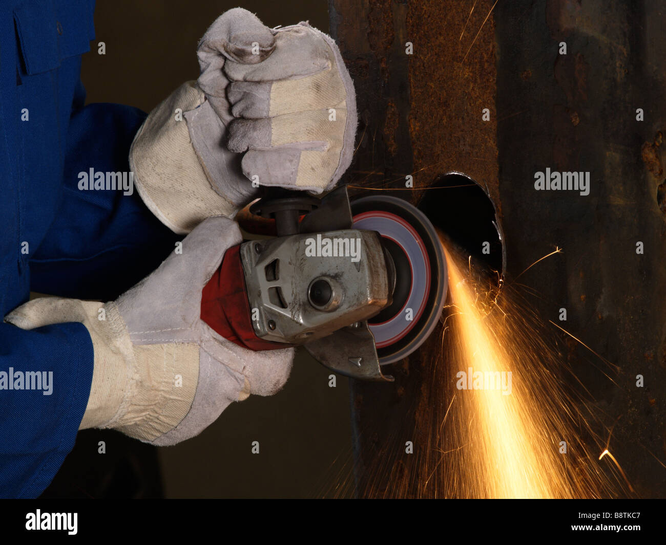 Hands with protective gloves using angle grinder on iron sparks heat