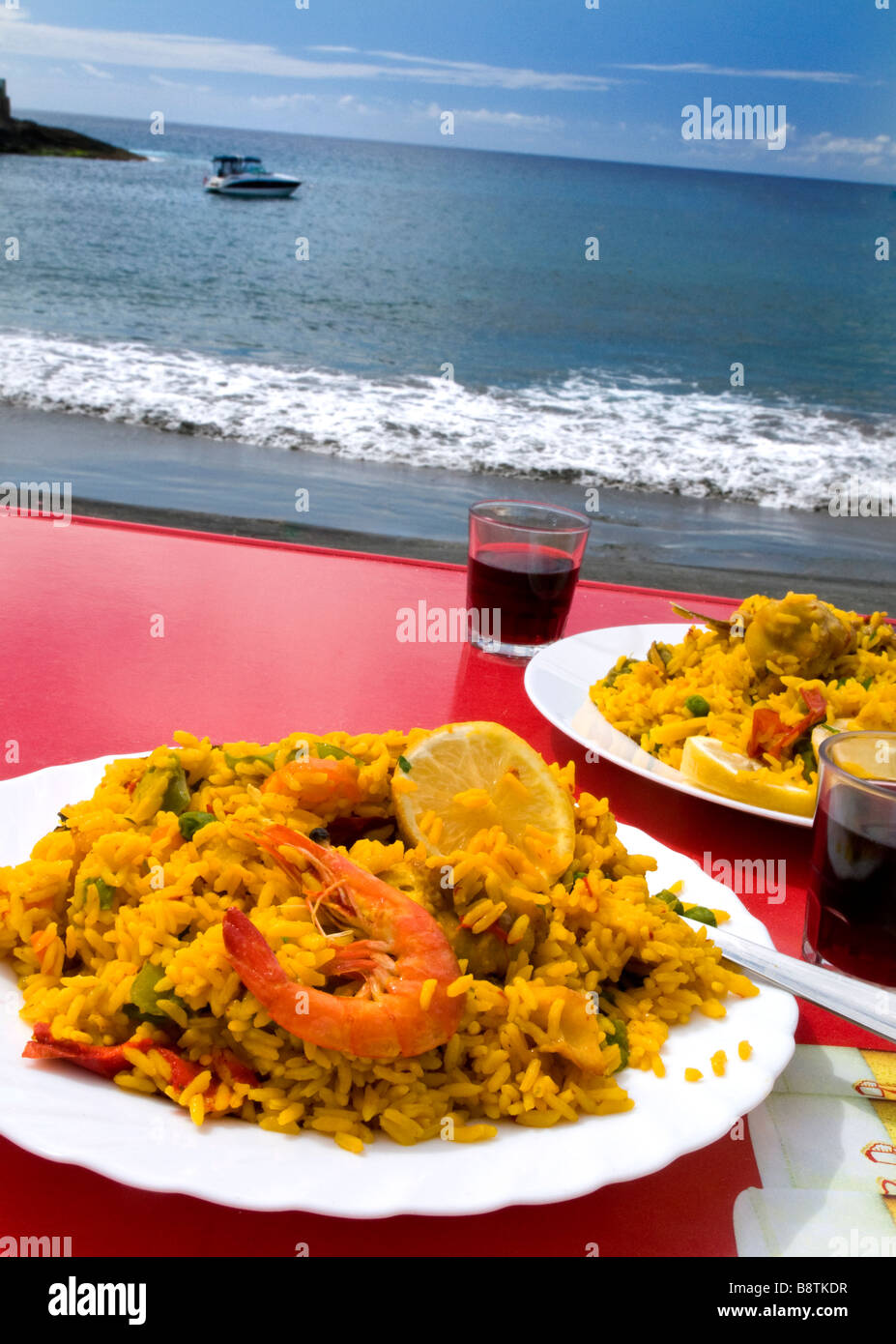 Seafood Paella Valenciana cooked and prepared by the sea, served traditionally with cool local red wine Spain Stock Photo