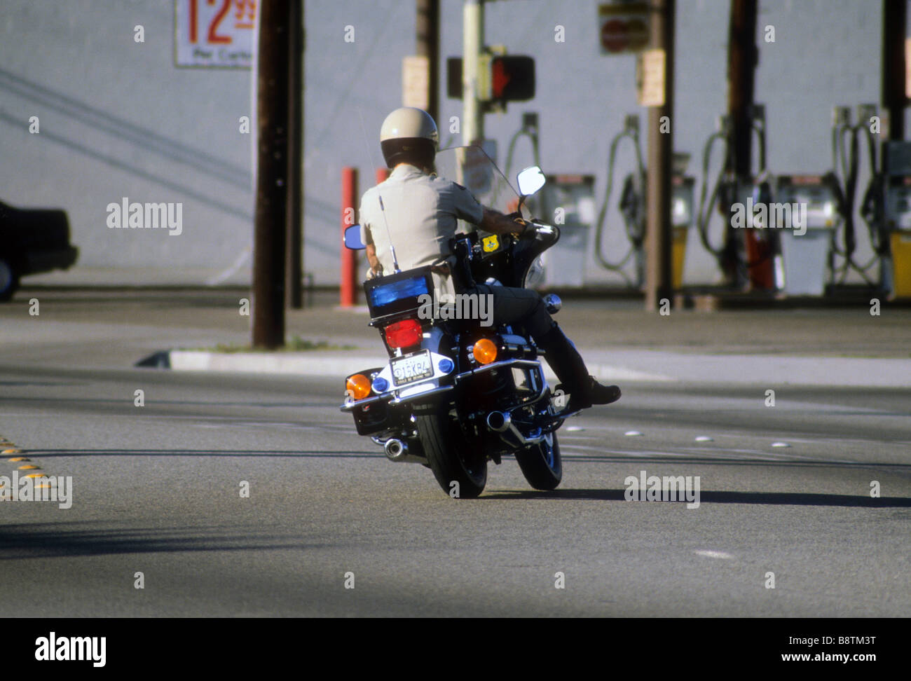 California Highway patrol officer on motor cycle motorcycle turns onto roadway Stock Photo