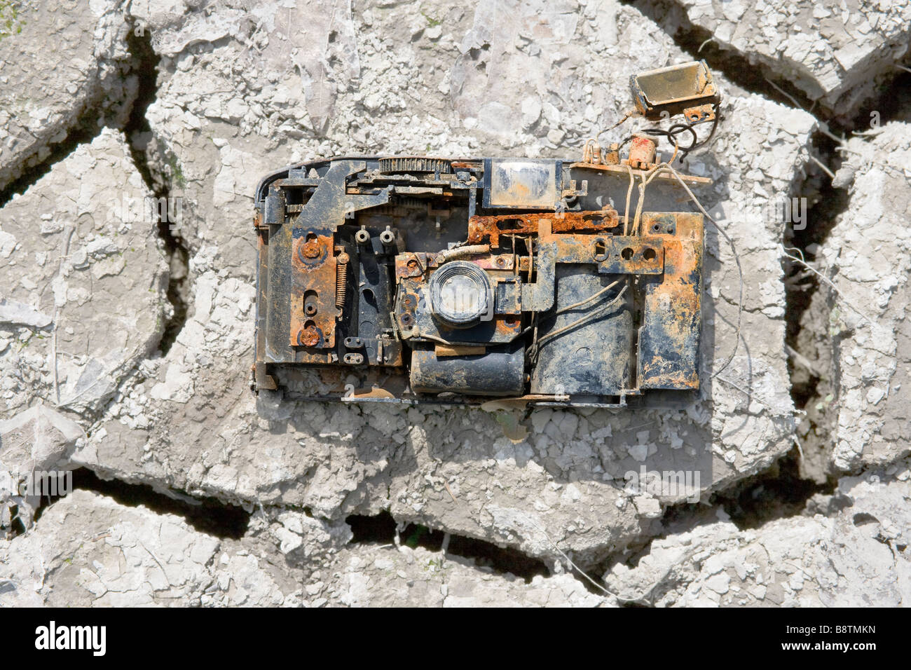 Broken discarded 35mm photo camera at the bottom of a lake, that's now dried up. Stock Photo