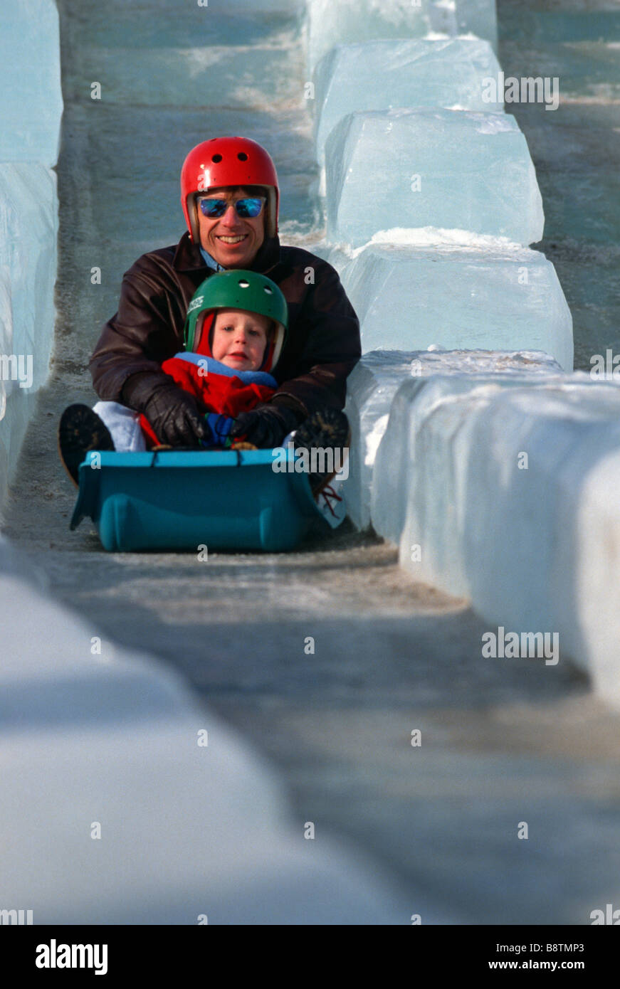 FATHER AND SON ON THE GIANT ICE SLIDE DURING ST. PAUL, MINNESOTA'S ANNUAL WINTER CARNIVAL. Stock Photo