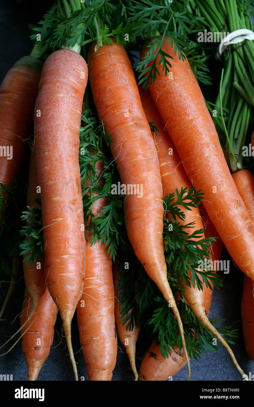 A bunch of carrots sit on a work top in a kitchen Stock Photo