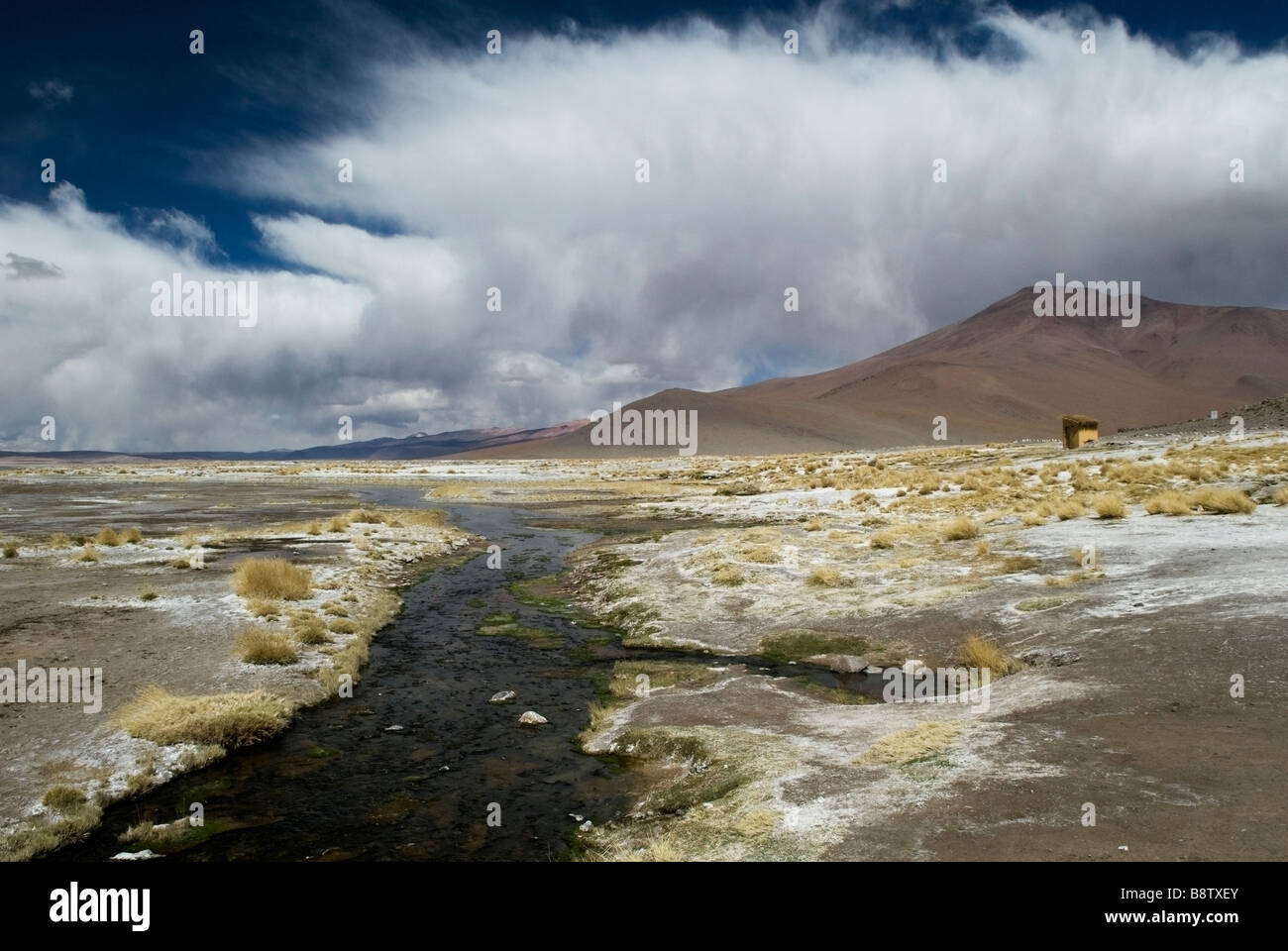 Striking clouds swirl above the hills surrounding the thermal pools of Termas de Polques high on the Bolivian Altiplano. Stock Photo